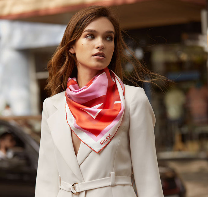 Model walks across street with Sésam modernist femme silk twill scarf around neck