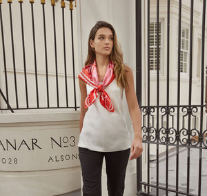 Model walks with Sésam queen foulard rouge and rose silk twill scarf around neck